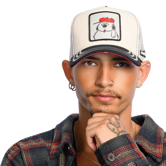 Man wearing beige and black twill trucker cap featuring a woven patch of Peanuts Olaf attached to the crown.