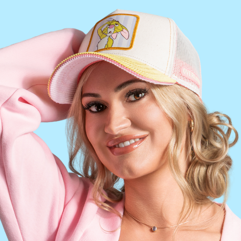 Model wearing the off-white Rabbit trucker cap with pink and yellow brim and off-white mesh sides.