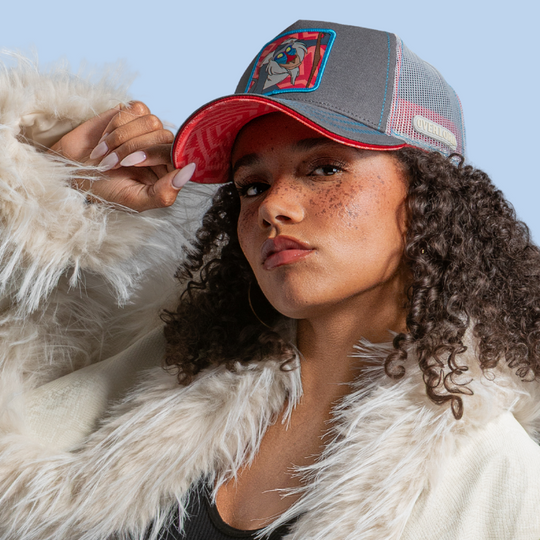 Model wearing the grey Rafiki from Disney's The Lion King retro trucker cap with a red brim and grey mesh side.
