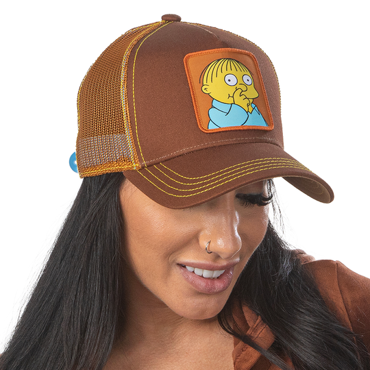 Woman wearing brown OVERLORD X The Simpsons Ralph Wiggum picking his nose trucker baseball cap hat with yellow stitching. PVC Overlord logo.