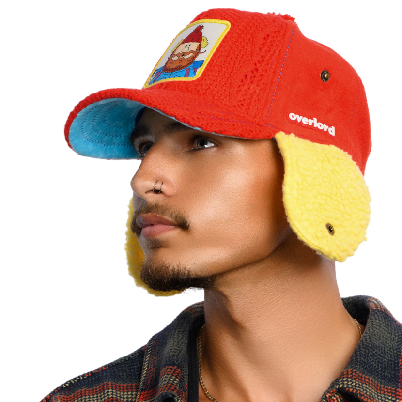 Person wearing a colorful hat with ear flaps and a cartoon character patch on a white background