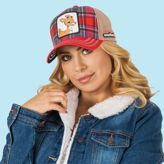 Woman wearing red and blue plaid trucker cap with khaki mesh featuring a woven patch of Rudolph the Red Nose Reindeer on the crown.