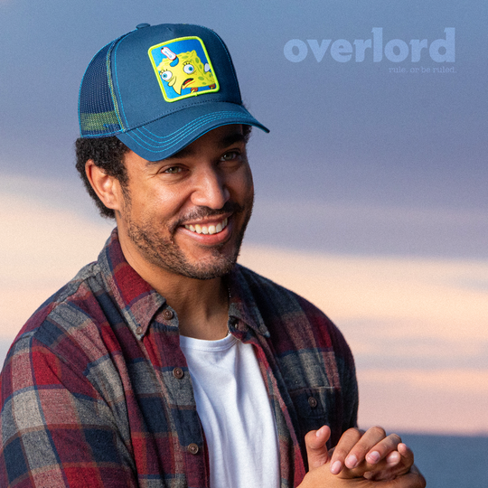 Man wearing navy OVERLORD X SpongeBob ChickenBob meme trucker baseball cap hat with blue stitching. PVC Overlord logo.