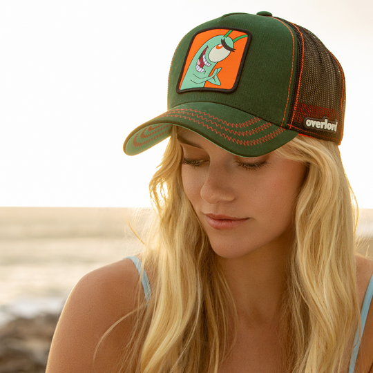 Woman wearing dark green OVERLORD X SpongeBob smiling Plankton trucker baseball cap hat with red stitching. PVC Overlord logo.