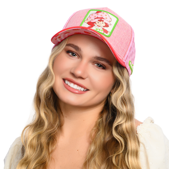 Woman wearing red and pink linen trucker cap hat with Strawberry Shortcake woven patch against a white background