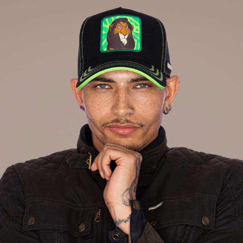 Model wearing the black Scar from Disney's The Lion King retro trucker cap with a green-trimmed brim and black mesh side.