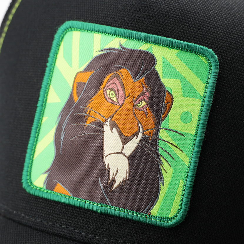 Close-up woven patch of Scar from Disney's The Lion King with a menacing glare, on a green patterned background with a green border, stitched onto a black corduroy-textured retro trucker cap.