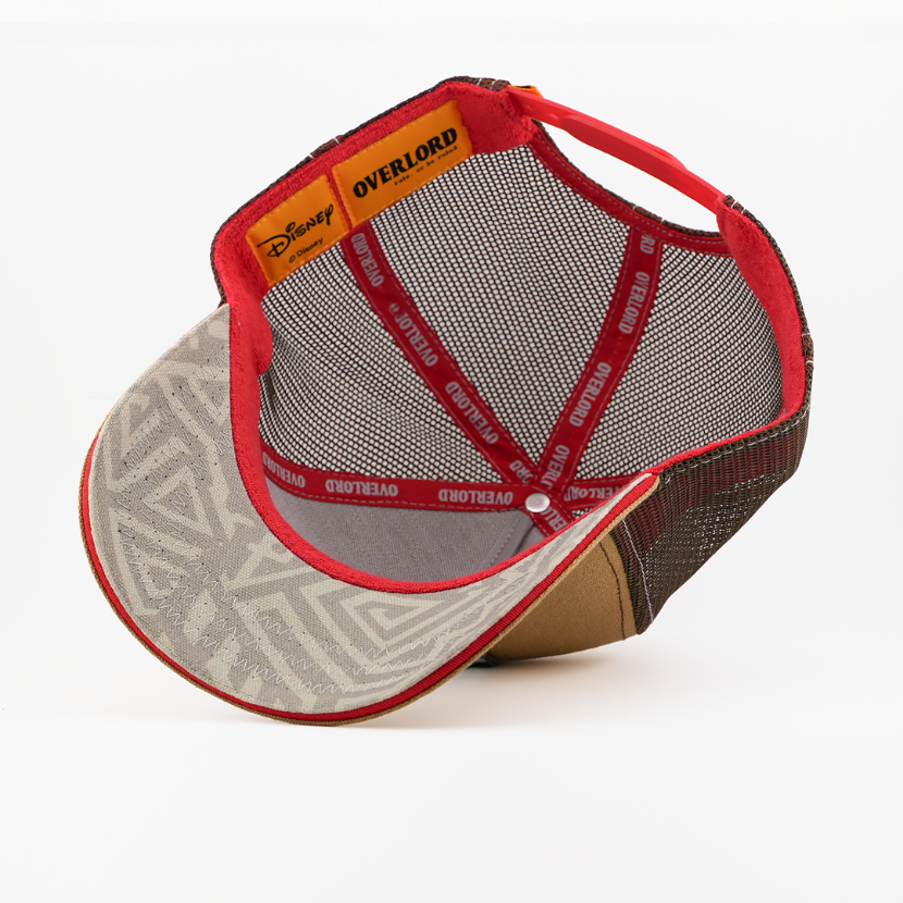 Underside of the Banzai from Disney's The Lion King retro trucker cap showing a grey patterned underbrim with red sweatband, brown mesh, Disney tag, and red Overlord branded taping with white text.