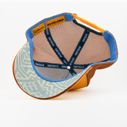 Underside of the Simba from Disney's The Lion King retro trucker cap showing a light blue patterned brim with blue edging, brown mesh crown, Disney tag, and navy Overlord branded taping with white text.