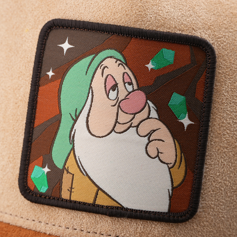Woven patch of Sleepy from Disney's Snow White and the Seven Dwarfs looking drowsy against a mine and gem-themed background, with a black border, stitched onto the tan suede-textured retro trucker cap.