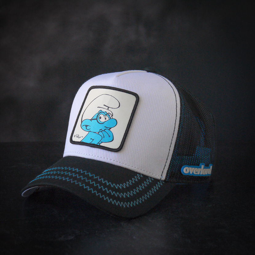Black and white twill trucker cap with black mesh featuring a woven patch of Brainy Smurf from the Smurfs attached to crown