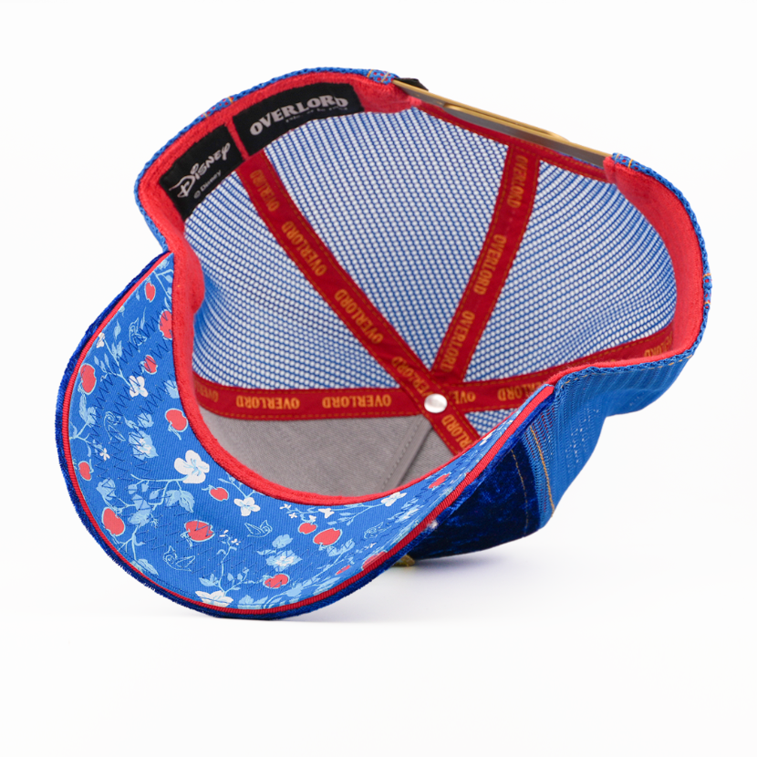Underside of the Snow White from Disney's Snow White and the Seven Dwarfs retro trucker cap showing a blue floral-print brim, a Disney tag, blue mesh crown, and red Overlord branded taping.