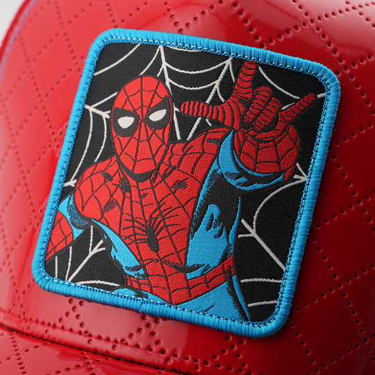 Close-up of a woven Marvel's Spider-Man patch with a blue border, stitched onto glossy red quilted cap fabric.