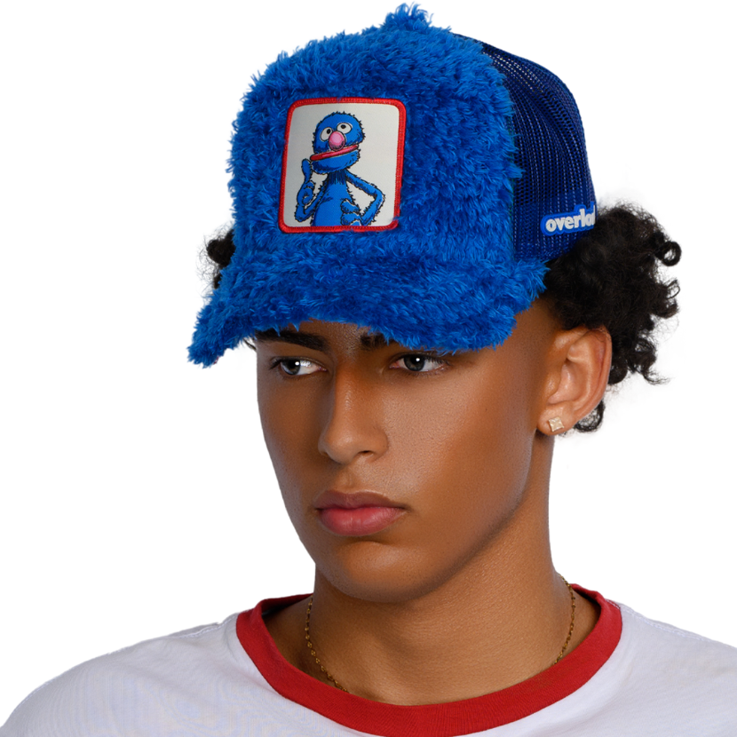 Man wearing blue faux fur trucker cap hat featuring Grover from Sesame Street on woven patch attached to crown