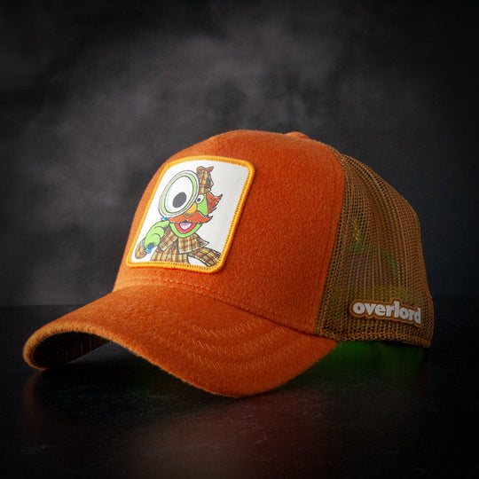 Brown cashmere wool trucker cap hat featuring Sherlock Hemlock from Sesame Street on woven patch attached to crown against black background