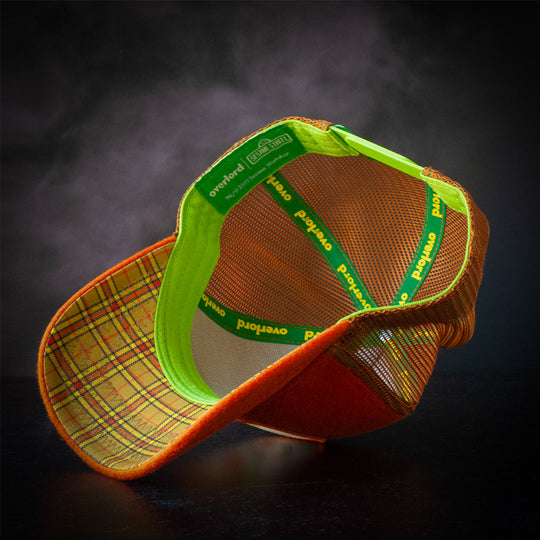 Inside view of brown cashmere wool trucker cap hat with olive green plaid printed on underbrim