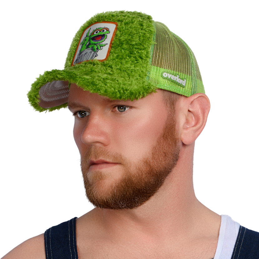 Man wearing green faux fur trucker cap hat featuring Oscar the Grouch from Sesame Street on woven patch attached to crown