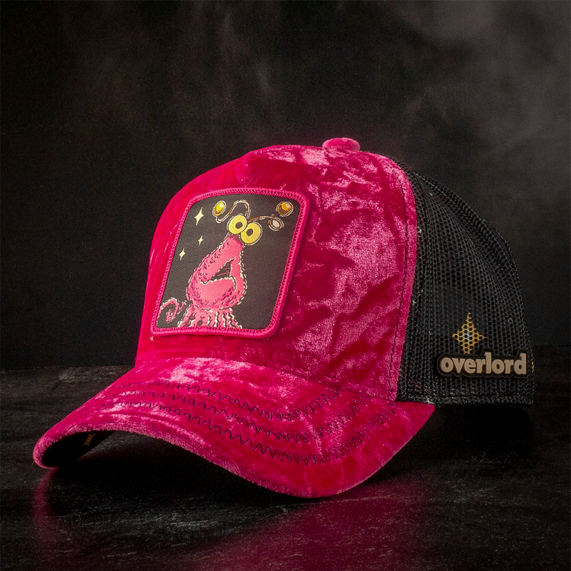 Hot pink crushed velvet trucker cap hat with Sesame Street pink yip martian woven patch against black background