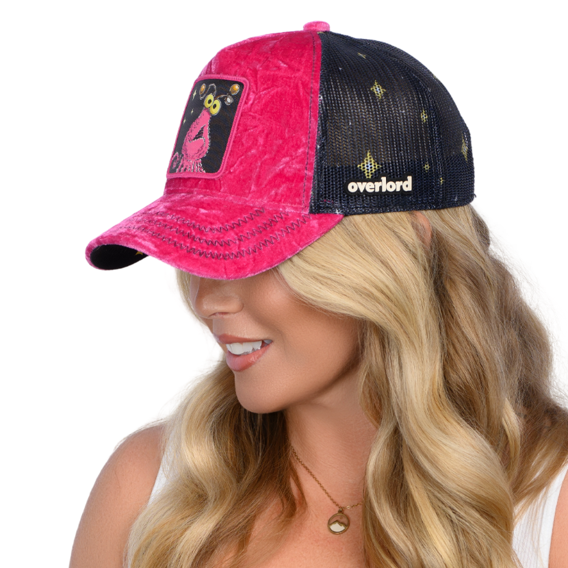 Woman wearing hot pink crushed velvet trucker cap hat with Sesame Street pink yip martian woven patch against white background