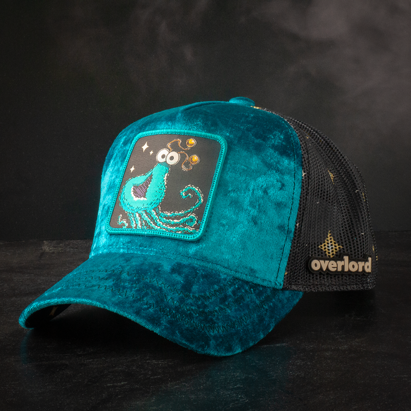 Blue crushed velvet trucker cap hat with Sesame Street blue yip martian woven patch against black background