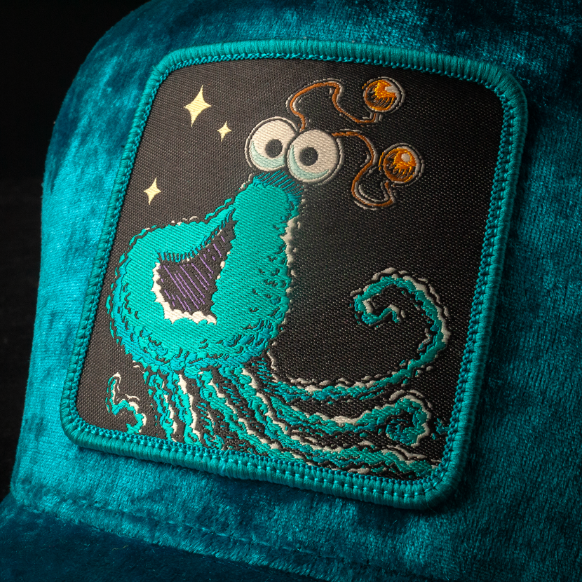 Woven patch of Sesame Street blue yip martian with a black background on a blue crushed velvet trucker cap hat