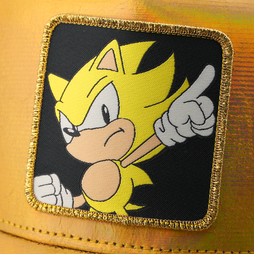 Woven patch of Super Sonic from Sonic the Hedgehog pointing forward, set against a black background with gold border, stitched onto the metallic gold retro trucker cap.