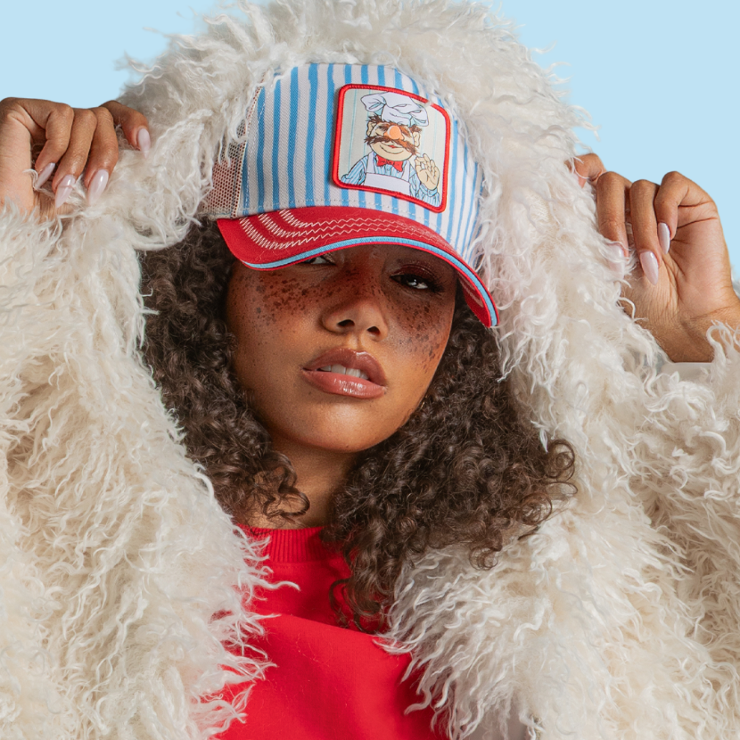 Model wearing the blue and white striped Swedish Chef from The Muppets retro trucker cap with a red brim and white mesh side.