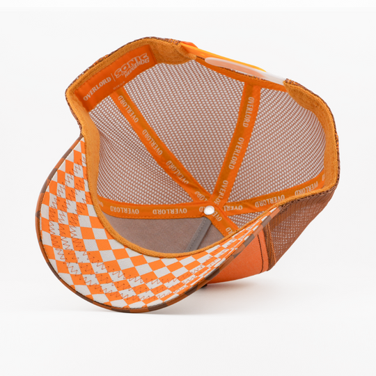 Underside of the Tails from Sonic the Hedgehog retro trucker cap, showing an orange and white argyle-pattern brim, Sonic the Hedgehog tag, brown mesh crown, and orange Overlord branded taping.