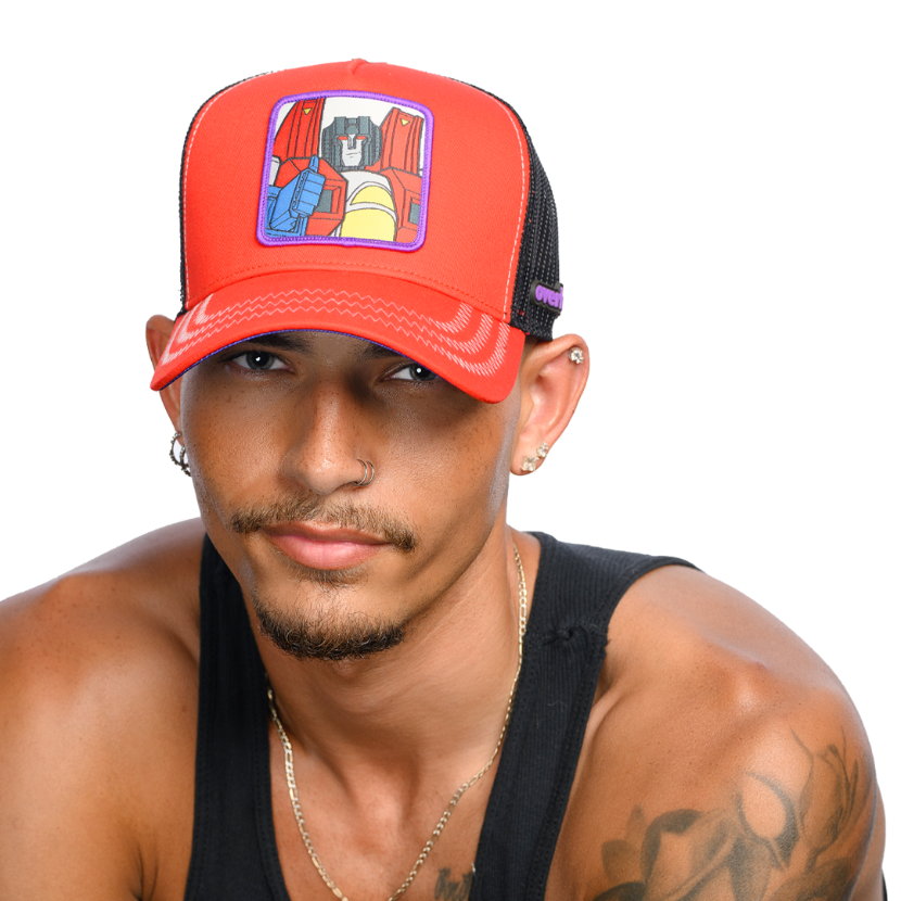 Man wearing red trucker cap hat featuring Starscream from Transformers on woven patch attached to crown