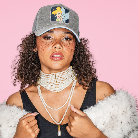 Model wearing the silver glitter-textured Tinker Bell from Disney's Peter Pan retro trucker cap with a matching brim.