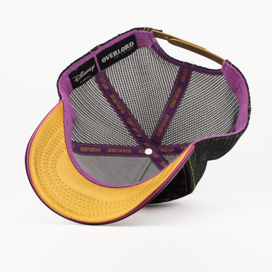 Underside of the Ursula retro trucker cap showing a gold brim, Disney tag, black mesh crown, and purple Overlord taping.