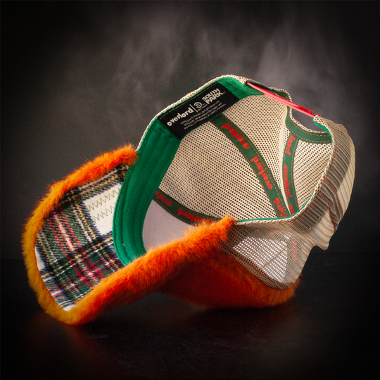 Inside view of faux fox fur trucker cap with white, green, red, and yellow soft flannel underbrim.