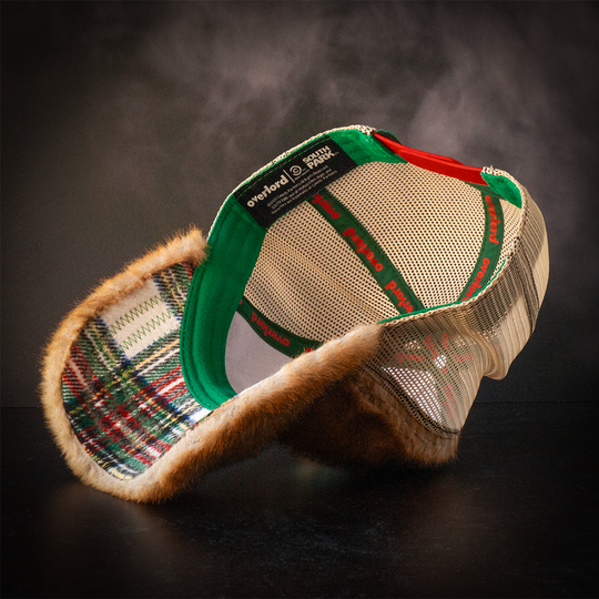 Inside view of faux raccoon fur trucker cap with soft white, green, red and yellow flannel underbrim.