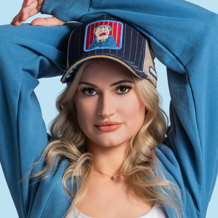 Model wearing the navy Waldorf from  The Muppets retro trucker cap with a mustard yellow brim and tan mesh side.
