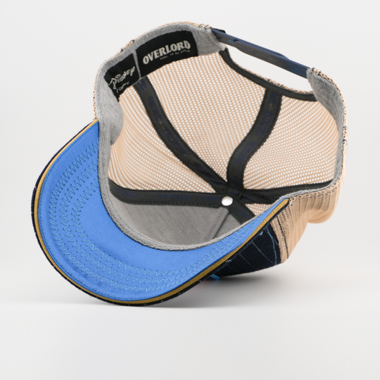 Underside of the Waldorf from The Muppets retro trucker cap, showing a solid light blue brim, a Disney tag, tan mesh crown, and black Overlord branded taping with white text.