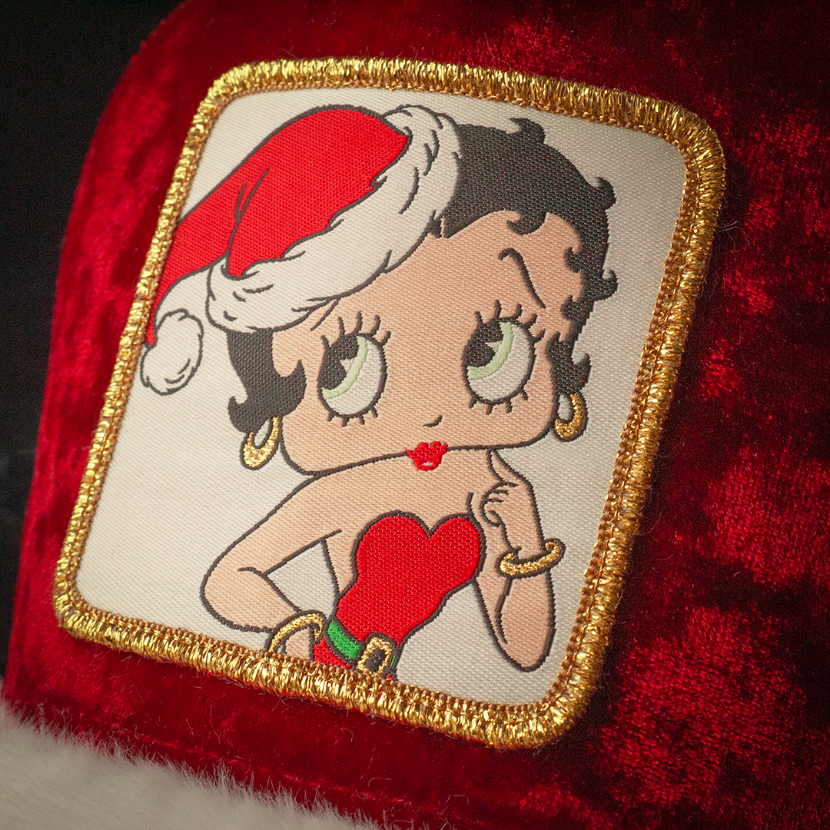 Close-up of a woven patch of Betty Boop wearing a Santa hat and red dress attached to the crown.