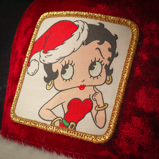 Close-up of a woven patch of Betty Boop wearing a Santa hat and red dress attached to the crown.