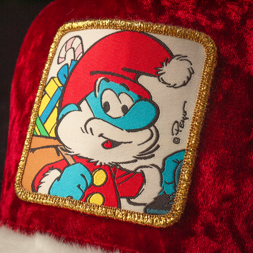 Close up of a woven patch of Papa Smurf from the Smurfs wearing a Santa suit and carrying a sack of presents attached to the crown.