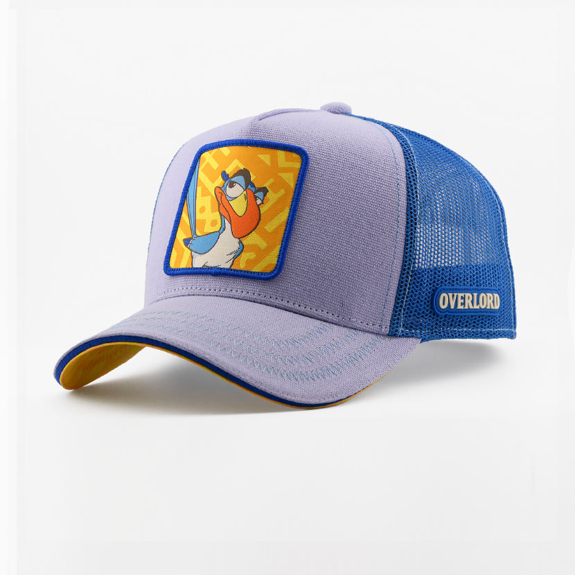 Purple corduroy-textured retro trucker cap with a woven Zazu from Disney's The Lion King patch on a yellow patterned background with a blue border, blue mesh back with Overlord logo.